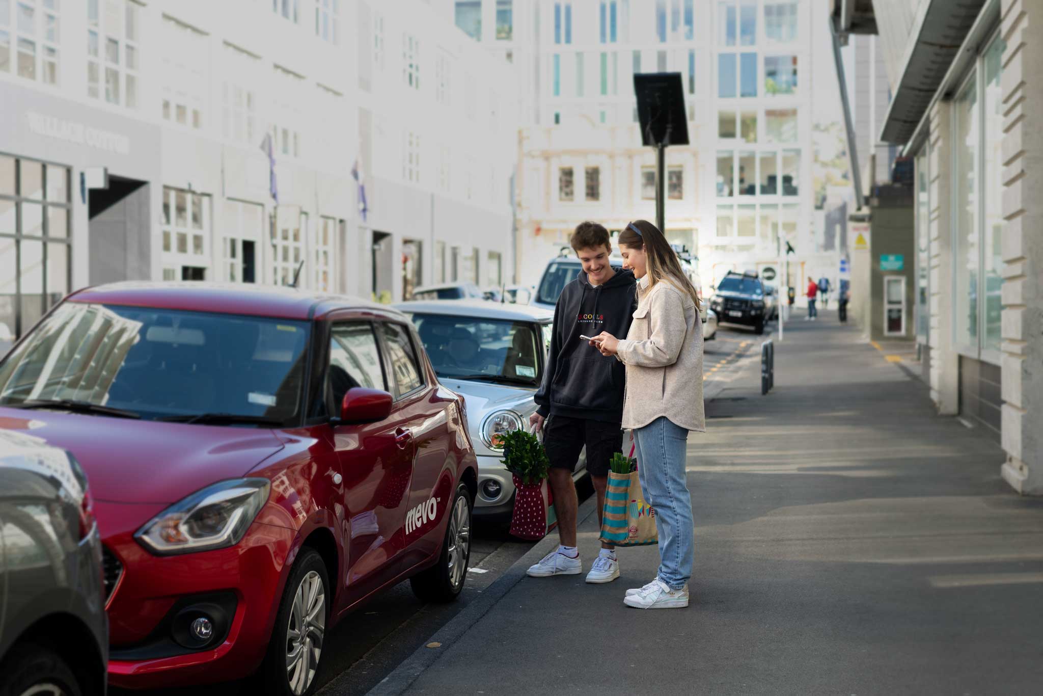 Man and woman next to Mevo Suzuki Swift on a city street
