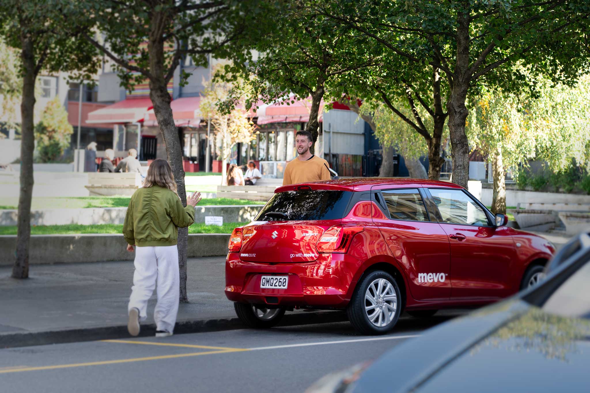 People on a city street with a Mevo Suzuki Swift in the foreground