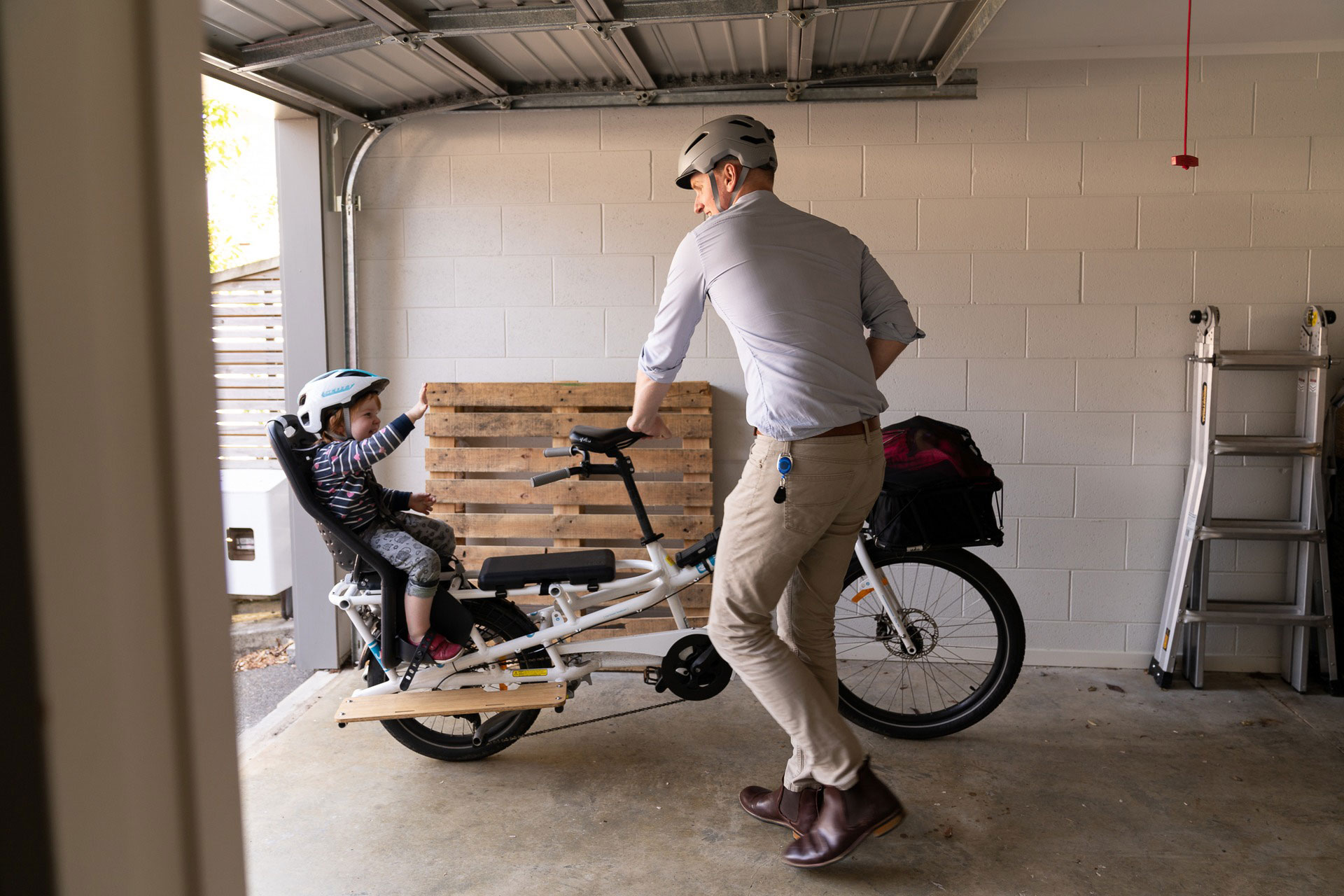 James taking his cargo bike out of the garage, with his child on the rear seat.