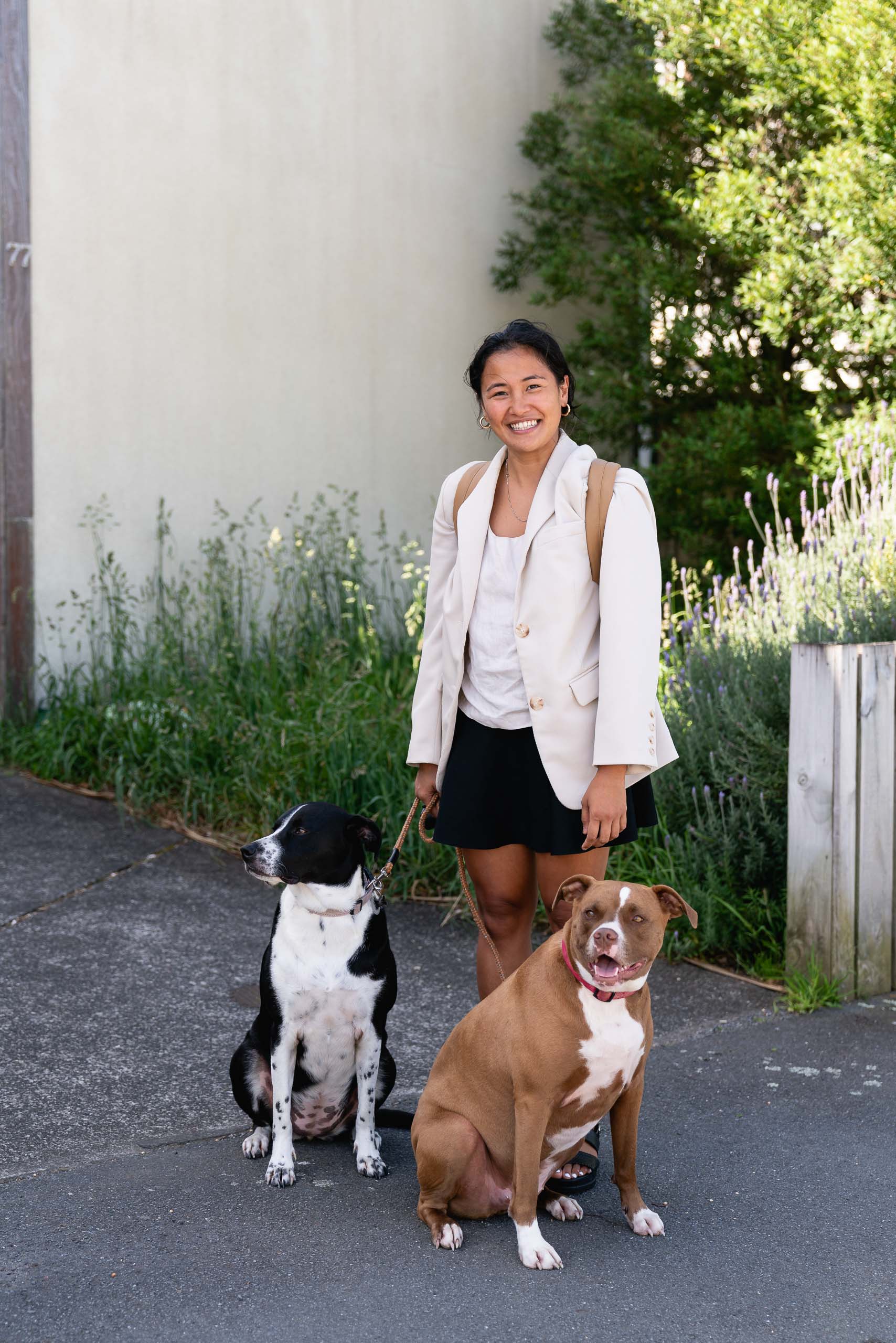 Tricia standing on the footpath with her dog Hattie, and friend's dog Nina, on leashes.